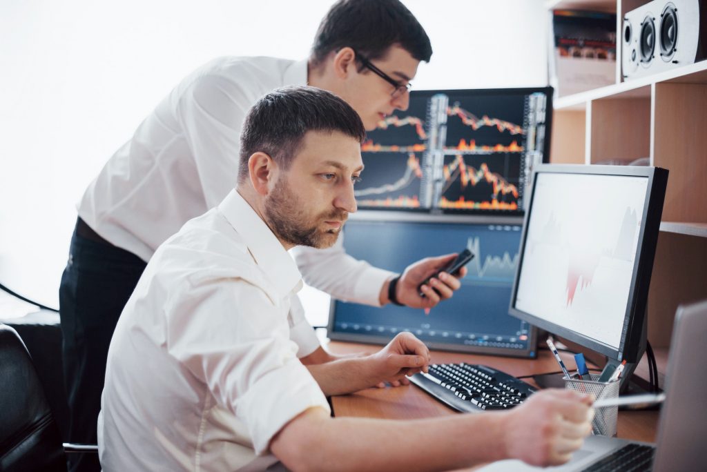 Businessmen trading stocks online. Stock brokers looking at graphs, indexes and numbers on multiple