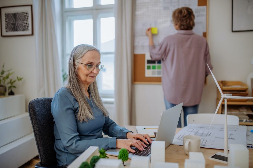 Happy mature women eco architects working together in office.