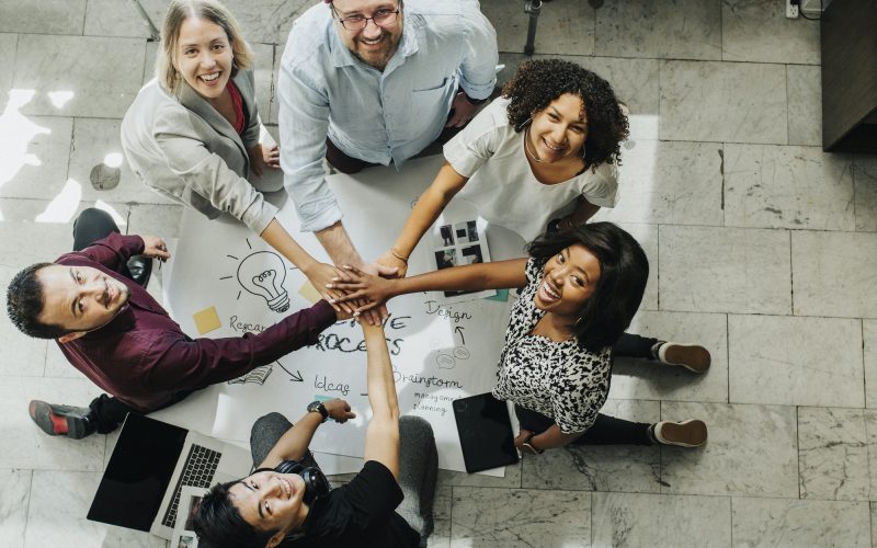 Happy team stacking hands on a creative ideas chart